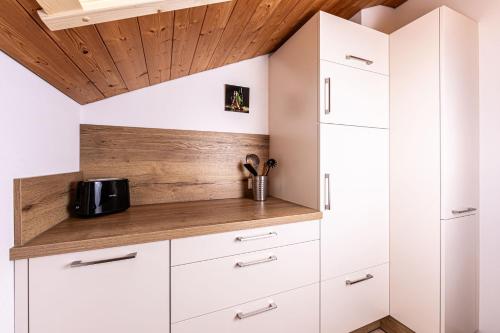 a kitchen with white cabinets and a wooden ceiling at Haus Familie Kosper Untersberger Kuschelnest in Bischofswiesen