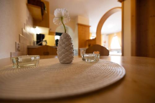 a flower in a vase on a plate on a table at Appartementhaus Olympia Schlössl in Neustift im Stubaital
