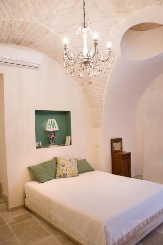 a bedroom with a bed and a chandelier at Pietre Gaie in Alberobello