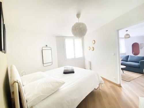 - une chambre blanche avec un lit et un canapé bleu dans l'établissement Le Grand 117 - Climatisation - Wifi - Parking proche, à Périgueux