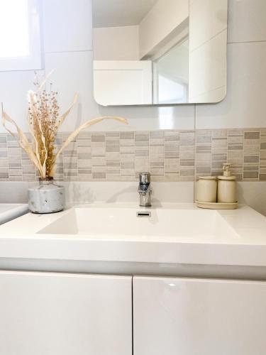une salle de bain avec un lavabo blanc et un miroir dans l'établissement Le Grand 117 - Climatisation - Wifi - Parking proche, à Périgueux