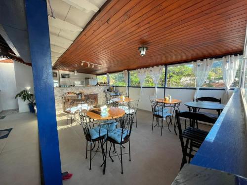 Un restaurante con mesas y sillas en una habitación con ventanas. en Brisa da Praia Colonial, en Ubatuba