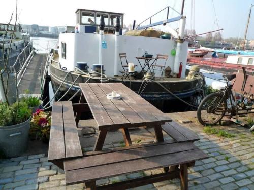 a picnic table and a bike next to a boat at Houseboat Captain's Quarters in Harbour Amsterdam in Amsterdam