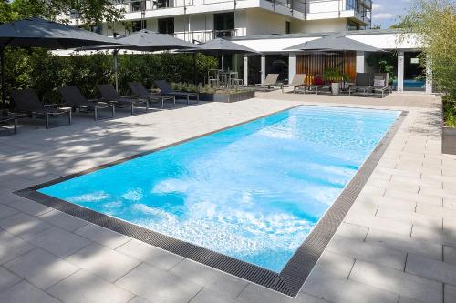 a large blue swimming pool with chairs and umbrellas at Schlosshotel Monrepos in Ludwigsburg