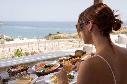 a woman sitting at a table with plates of food at Horizon Suites Milos in Paliochori