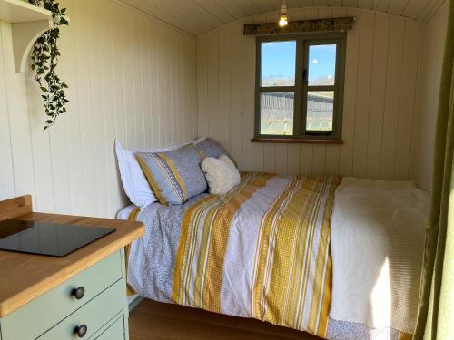 a small bedroom with a bed and a window at Shepherd Huts on a Farmstay in Michelmersh