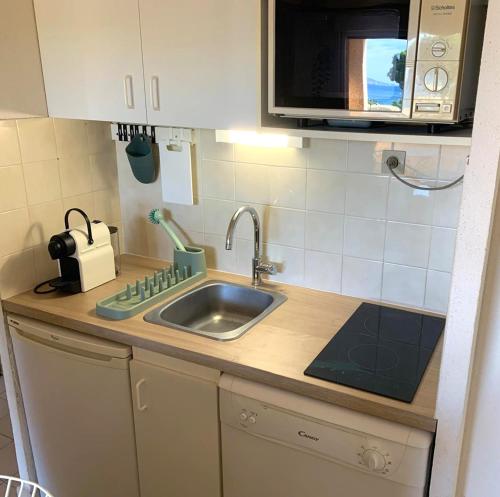 un comptoir de cuisine avec un évier et un micro-ondes dans l'établissement Appartement face à la mer avec parking, à La Londe-les-Maures