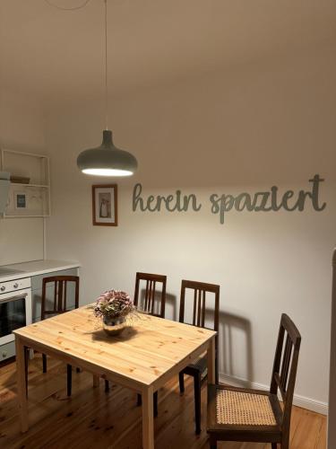 a dining room table with chairs and a sign on the wall at Viki54 FeWo04 "hereinspaziert", Monteurs- und Ferienwohnung in Velten
