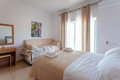 a bedroom with two beds and a couch and a window at Zacharias apartments in Himare