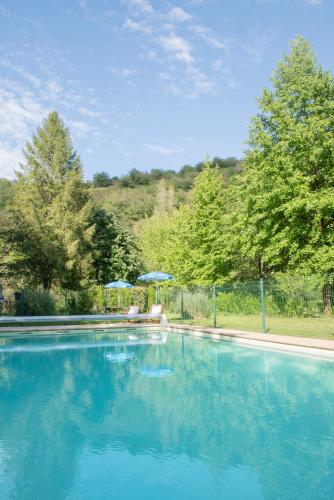 une grande piscine avec de l'eau bleue et des parasols dans l'établissement Camping Pittoresque, à Saint-Parthem