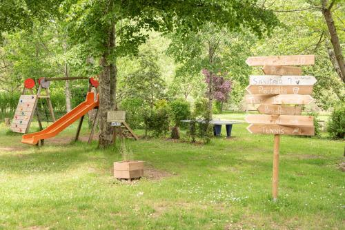 un parc avec une aire de jeux avec un toboggan et un panneau dans l'établissement Camping Pittoresque, à Saint-Parthem