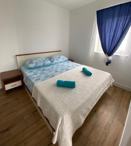 a bedroom with a bed with two blue pillows on it at Apartments Villa Dalmatina in Vodice