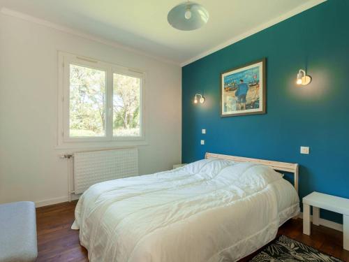 une chambre avec un lit avec un mur bleu dans l'établissement Maison charmante à Carnac, 3 pièces, jardin, à 300m de la Rivière de Crac'h - FR-1-477-247, à Carnac