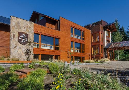 a large wooden building with a stone at Huenú by DOT Boutique in Villa La Angostura
