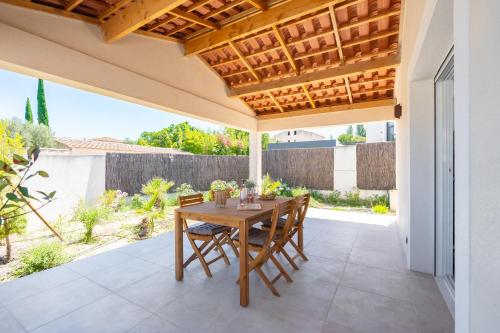 une table et des chaises en bois sur une terrasse dans l'établissement Villa Lavande, à Marignane