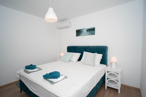 a bedroom with a white bed with a green headboard at Villa Paradise On The River in Blagaj
