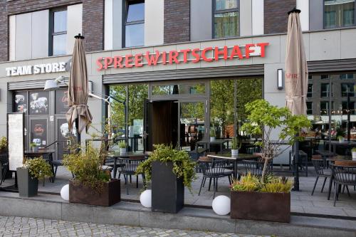 a restaurant with tables and chairs and umbrellas at Hotel Indigo Berlin - East Side Gallery in Berlin