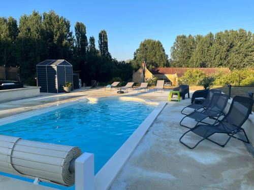 a swimming pool with chairs next to a house at Maison 6km de Sarlat piscine chauffée et jacuzzi in Saint-Vincent-le-Paluel