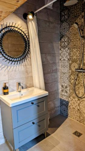 a bathroom with a sink and a shower with a mirror at Vila Vynuogyne in Paberžė