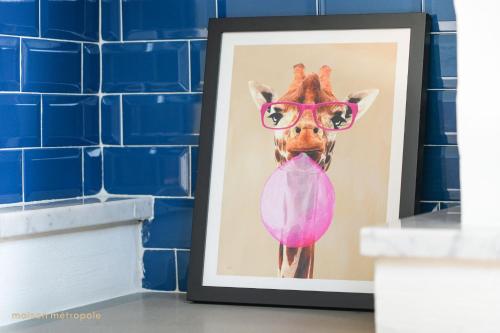 a painting of a giraffe wearing pink glasses at Art House Arsenale in Turin