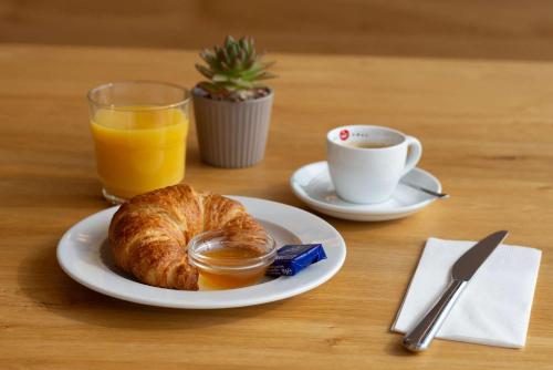 a plate with a croissant and a cup of coffee and orange juice at Best Western Hotel Kiefersfelden in Kiefersfelden