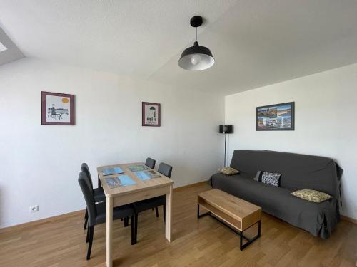 un salon avec un canapé et une table dans l'établissement L'air marin Apt avec belle terrasse vue dégagée séjour lumineux 10 mn à pied mer et centre Port en Bessin, tous commerces et restaurants, proche Bayeux et Omaha Beach, à Port-en-Bessin-Huppain