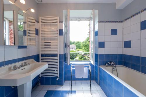 La salle de bains bleue et blanche est pourvue d'une baignoire et d'un lavabo. dans l'établissement Maison de Maître - calme-campagne-nature- CAUTION OBLIGATOIRE SWIKLY, à Cernoy-en-Berry
