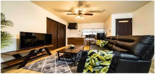 a living room with a leather couch and a flat screen tv at 64, Shiomi , Second floor of the apartment, 潮見2F in Tokyo