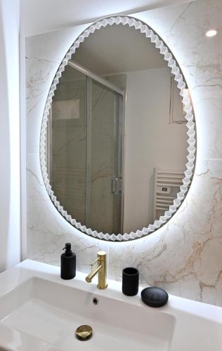 a bathroom with a large mirror over a sink at Une parenthèse amoureuse in Sens