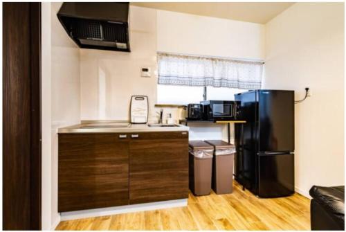 a small kitchen with a black refrigerator and a table at 64, Shiomi , Second floor of the apartment, 潮見2F in Tokyo