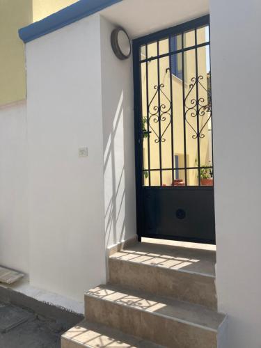 a black door on a white building with stairs at SOL Aegina Town House in Egina