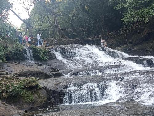 a group of people standing in front of a waterfall at Rb guest house in Mawlynnong