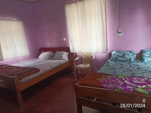a bedroom with two beds and a table and a chair at Rb guest house in Mawlynnong
