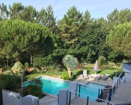 une cour arrière avec piscine et un aménagement paysager avec des arbres dans l'établissement Villa Sérénité 4 étoiles sans vis à vis 4ch8p près dune du Pilat Clim piscine, à La Teste-de-Buch