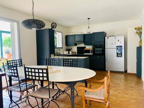 une cuisine avec une table, des chaises et un réfrigérateur dans l'établissement Villa Zen, à Pinet