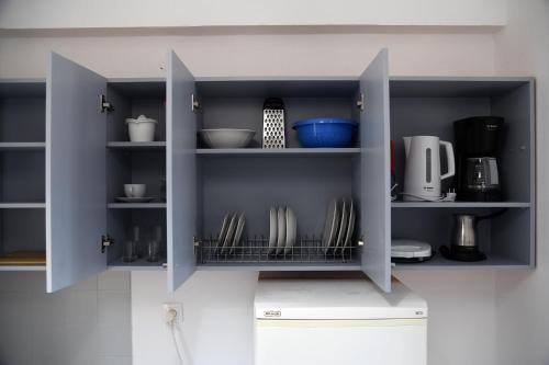 a cupboard with plates and other kitchen utensils at Studios Αποστόλης Selianitika in Aígio