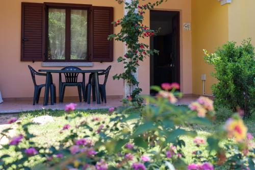 a patio with a table and chairs and flowers at Residence Oasi Anfiteatro in Porto Ottiolu