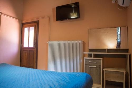a bedroom with a blue bed and a television at Το καλύβι της γιαγιάς in Damouchari