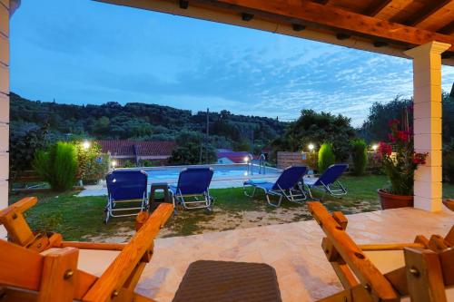 a patio with chairs and a table and a pool at Green Family Villa in Agios Ioannis