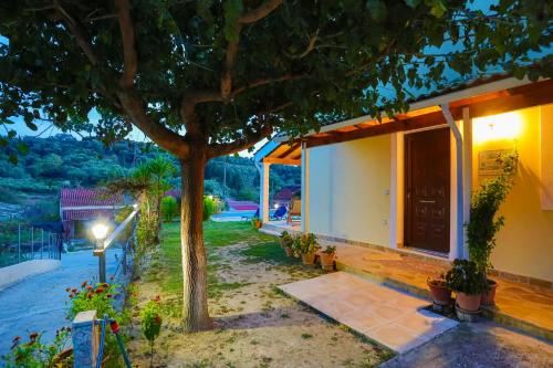a house with a tree in front of it at Green Family Villa in Agios Ioannis