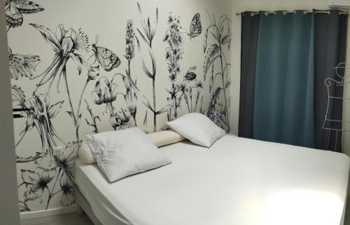 une chambre avec un lit avec un papier peint fleuri dans l'établissement la Recouturière, à Saint-Thibéry