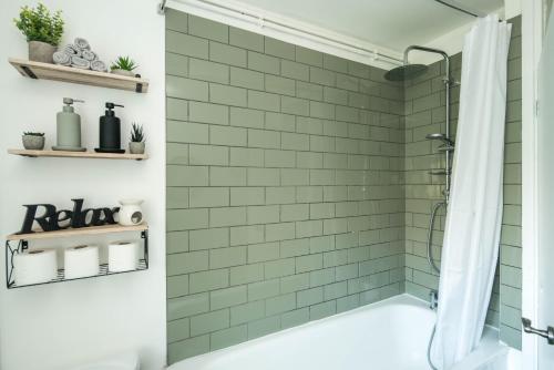 a bathroom with green subway tile and a shower at 1 Bedroom apartment Kentish town in London
