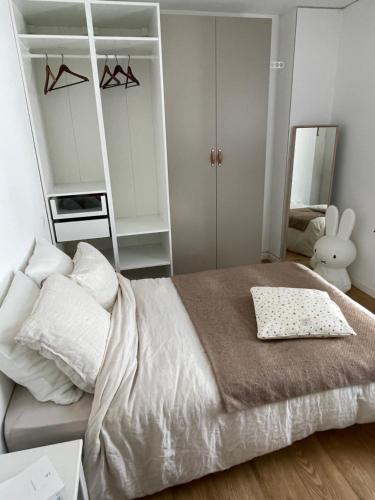 - une chambre avec un grand lit blanc et une étagère dans l'établissement Maison avec piscine - Bidart campagne proche plages, à Bidart