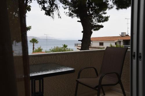 a table and chair on a balcony with a view of the ocean at Studios Αποστόλης Selianitika in Aígio