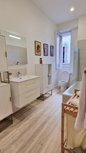 une salle de bain blanche avec un lavabo et des toilettes dans l'établissement Jazzy et Spacieux Appartement Prom des Anglais, à Nice