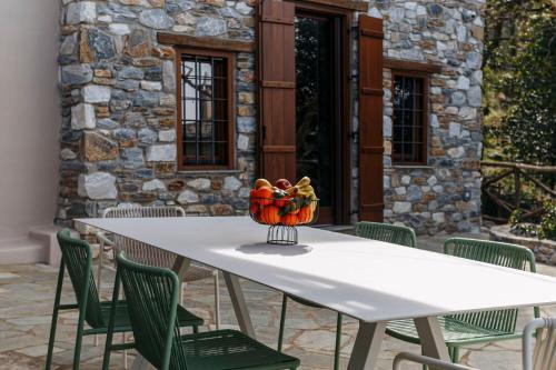 a white table with a vase of fruit on it at Trees Ikies in Mouresi