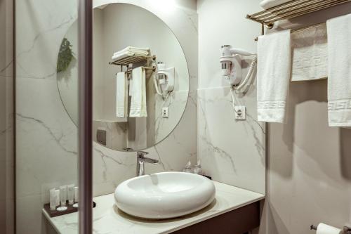 a white bathroom with a sink and a mirror at La Strada The Villa in Piteşti