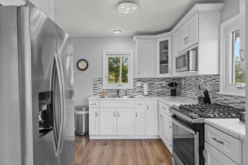 a kitchen with white cabinets and a stainless steel refrigerator at Charming Duplex on Main in St. Charles