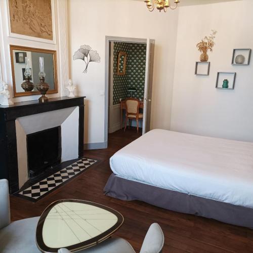 une chambre d'hôtel avec un lit et une cheminée dans l'établissement Le Relais des Roses- Chambres d'hôtes, à Vatan