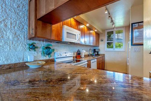 a kitchen with a marble counter top and wooden cabinets at Kanai A Nalu 302 in Wailuku